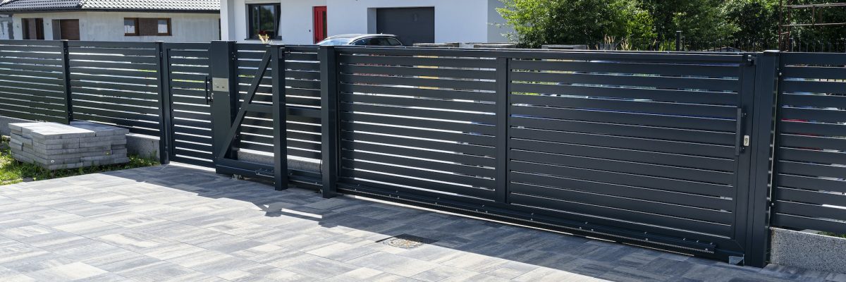 A modern panel fence in anthracite color, a visible sliding gate to the garage and a wicket.