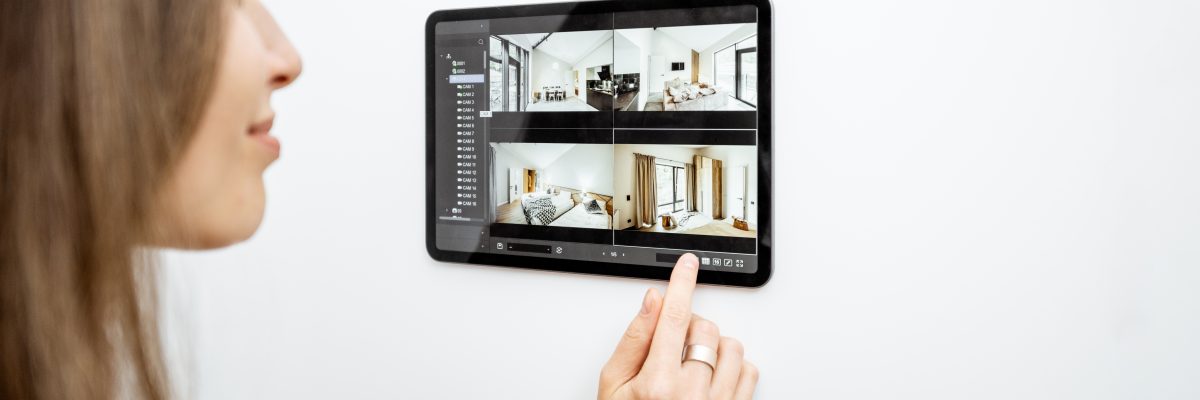 Woman controlling home with video cameras and digital tablet